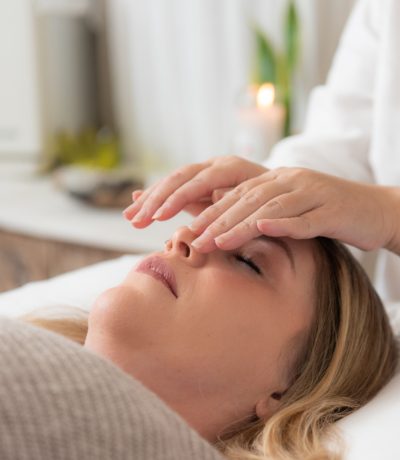 Client lying on a treatment table while a Reiki practitioner performs a Reiki session.